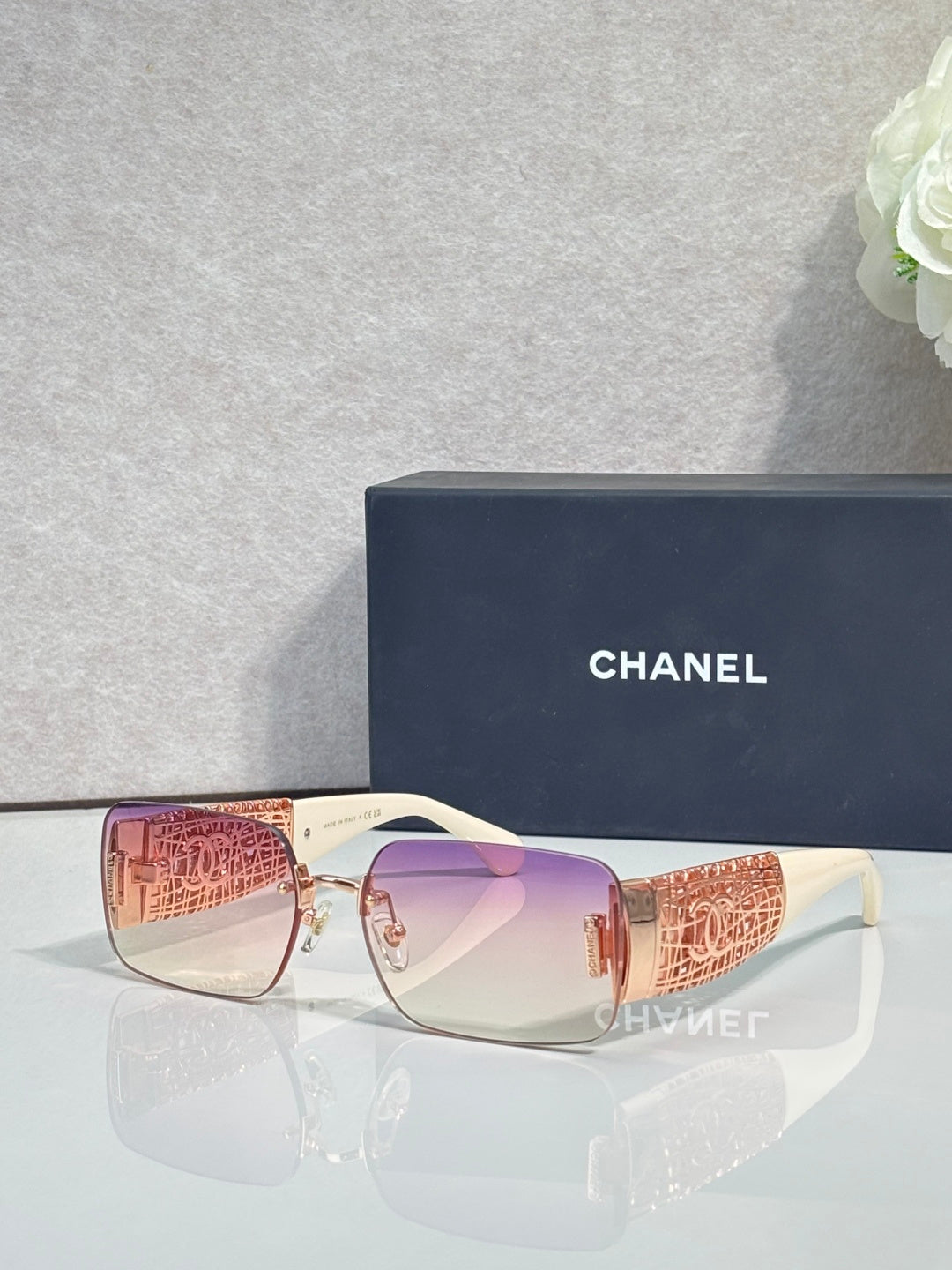 Chanel sunglasses with pink lenses, rose-gold frame, orange patterned temple tips