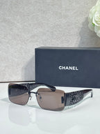 Chanel sunglasses with brown lenses, silver frame, black patterned temple arms
