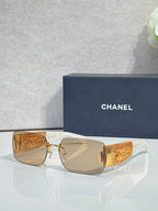 Chanel sunglasses with tan lenses, gold-tone frame, orange patterned temple arms