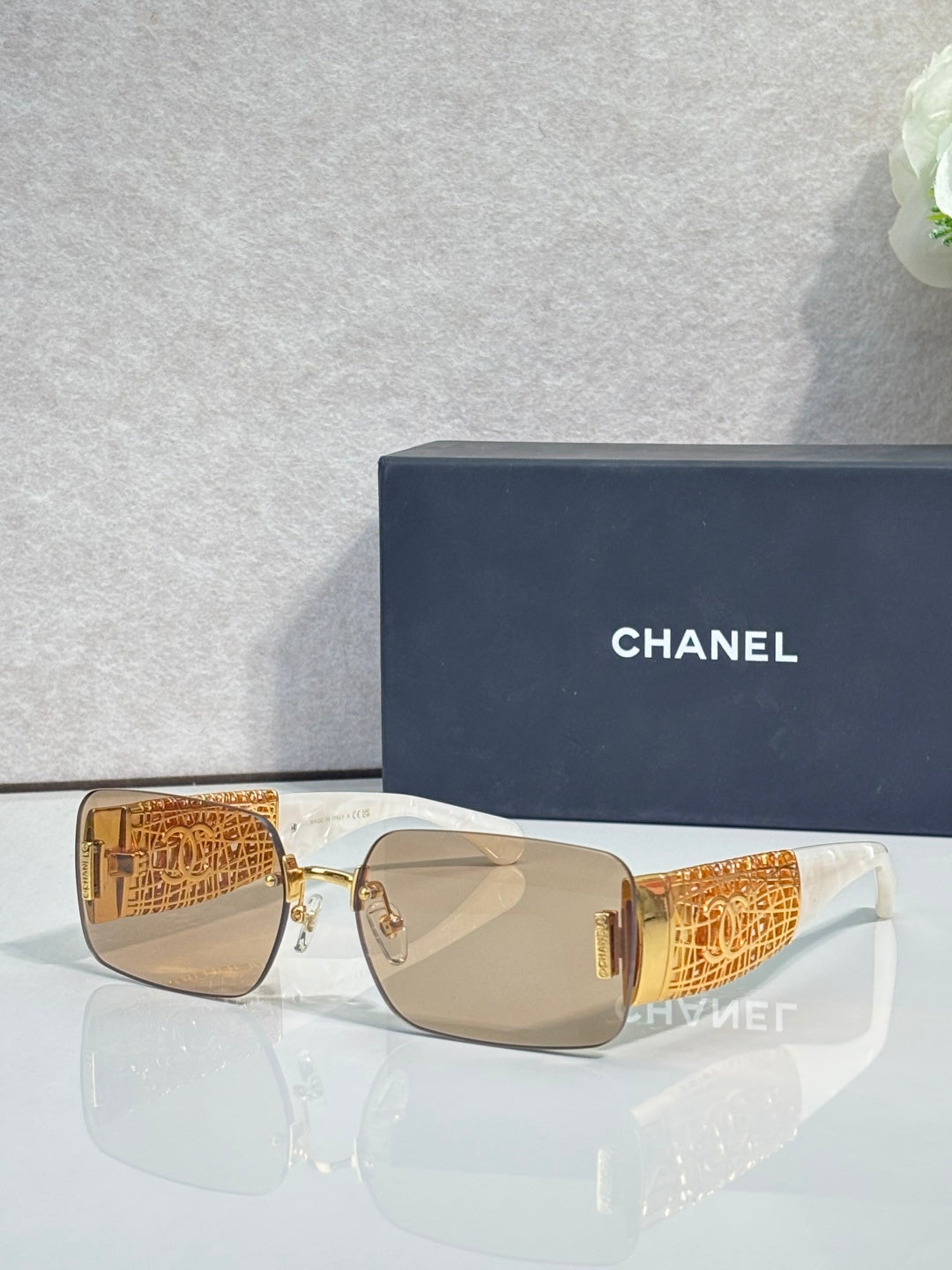 Chanel sunglasses with tan lenses, gold-tone frame, orange patterned temple arms