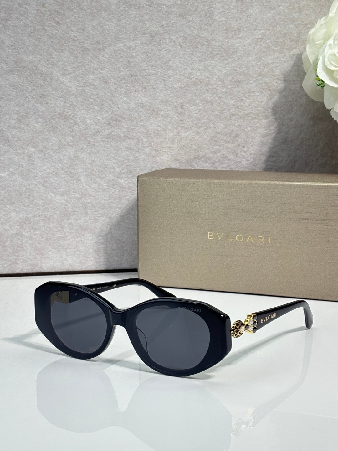 Bvlgari sunglasses with dark lenses, navy round frames, and light gray temple details