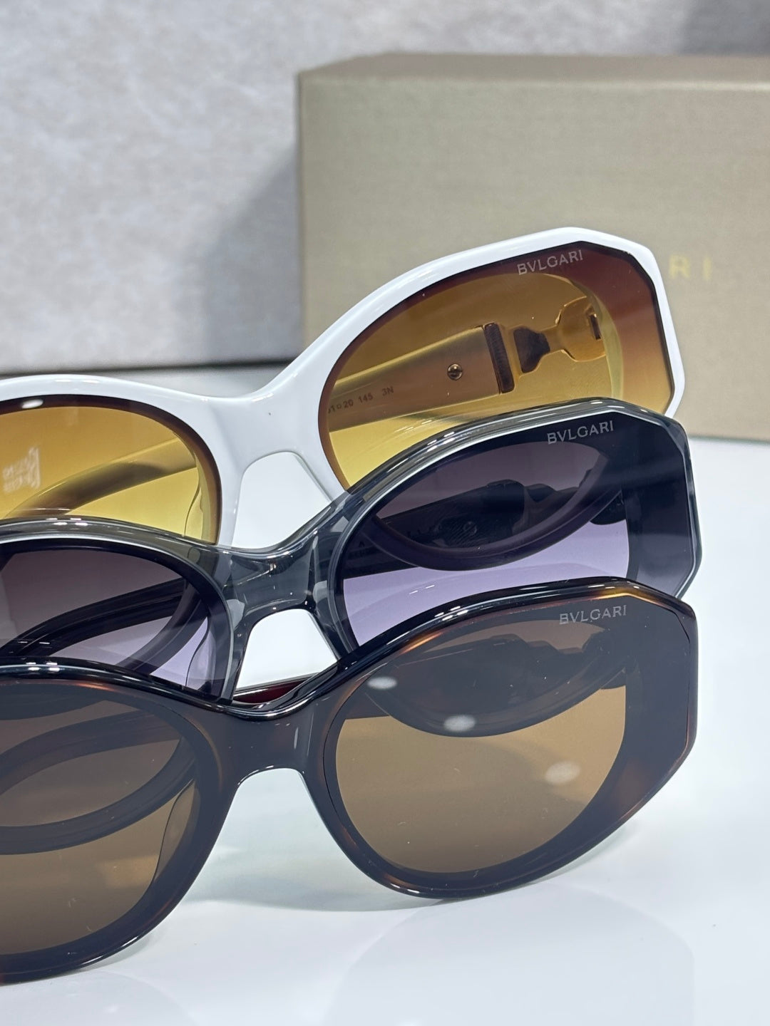 Bvlgari sunglasses close-up with white frame and dark blue lens, gold Bvlgari branding
