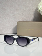 Bvlgari sunglasses with dark lenses and black round frames, clear temple accents