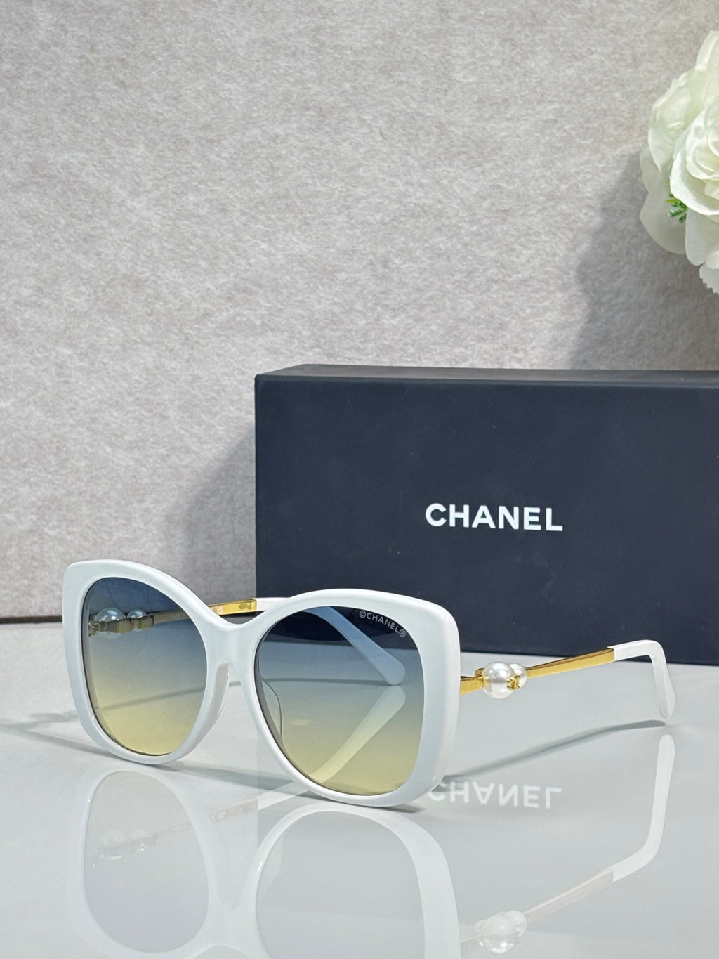 Chanel glasses with white cat-eye frames, tinted blue lenses, gold-tone accents