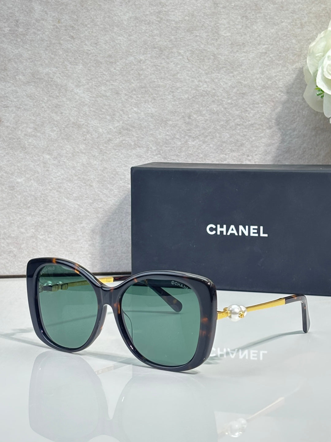 Chanel glasses with dark blue frames, green-tinted lenses, gold-tone temples