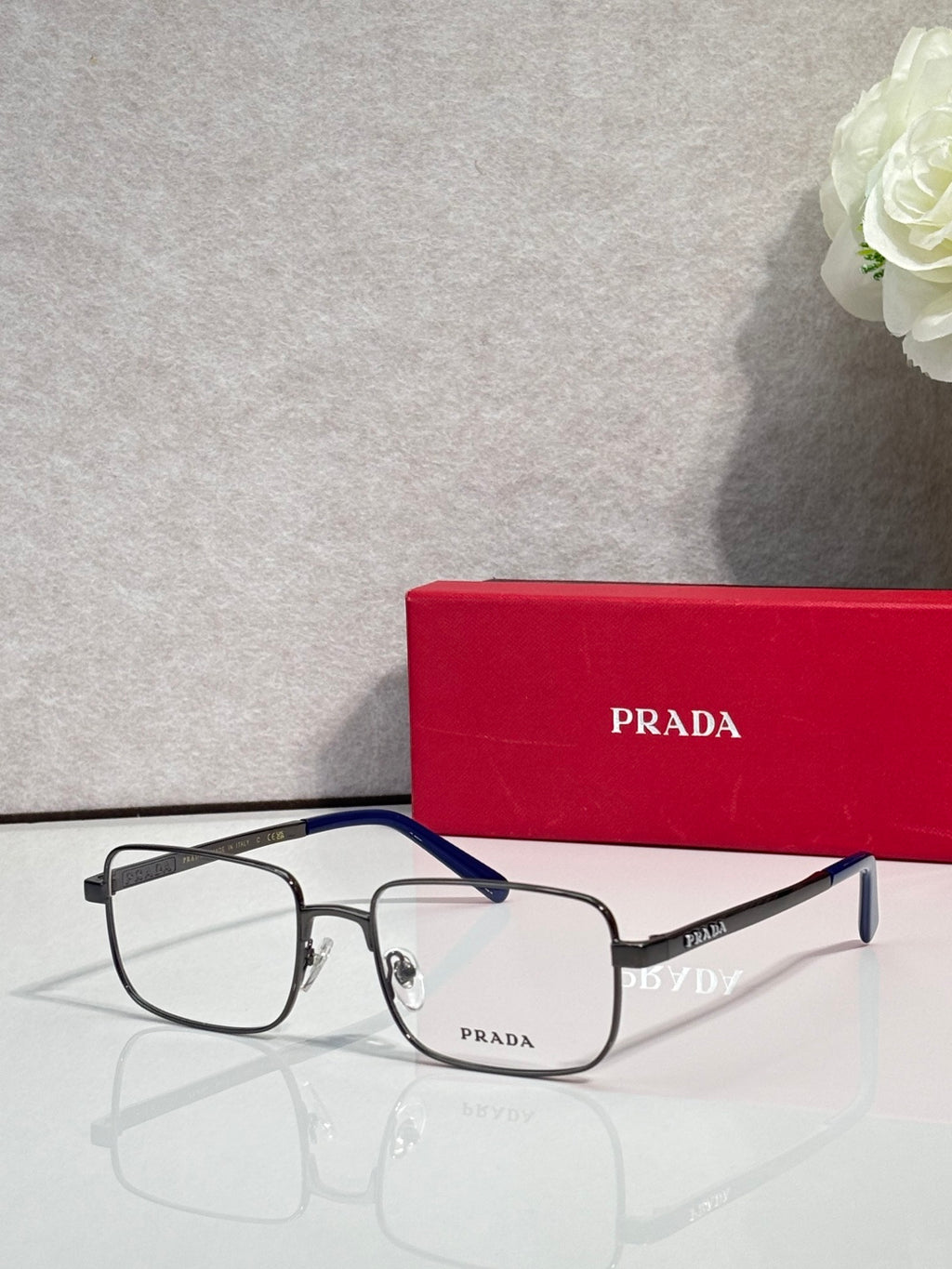 Prada rectangular eyeglasses with dark frames and clear lenses.