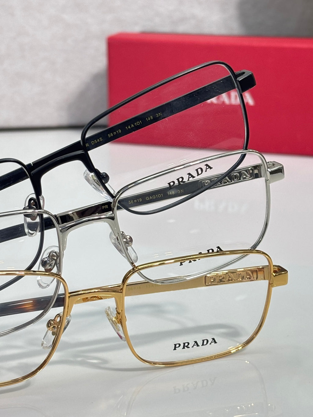 Prada rectangular eyeglasses set with silver and gold frames and clear lenses.