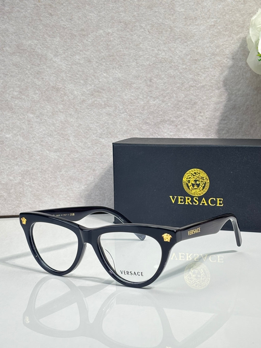 Versace optical glasses, dark blue frame with gold logo accents, clear lenses.
