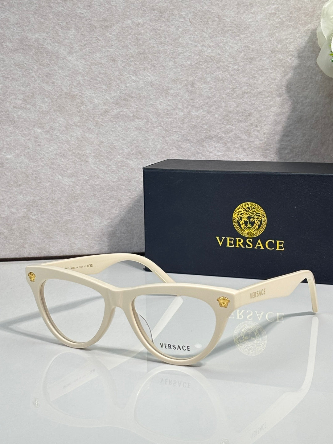 Versace optical glasses, white frame with gold logo accents, clear lenses.