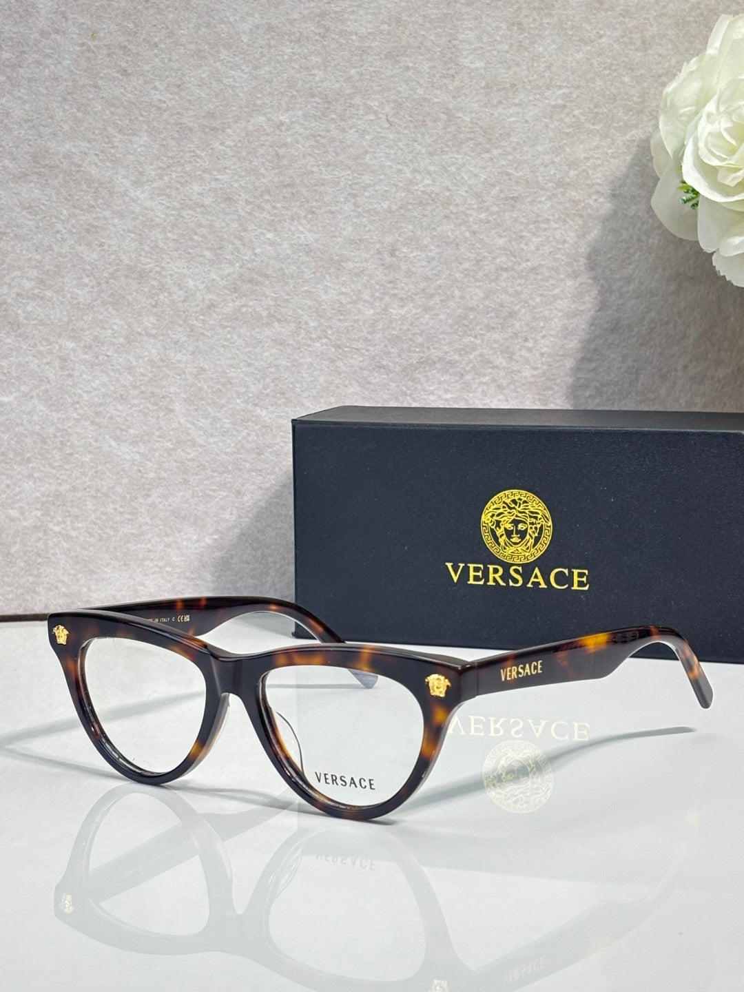 Versace optical glasses, tortoiseshell frame with gold logo accents, clear lenses.
