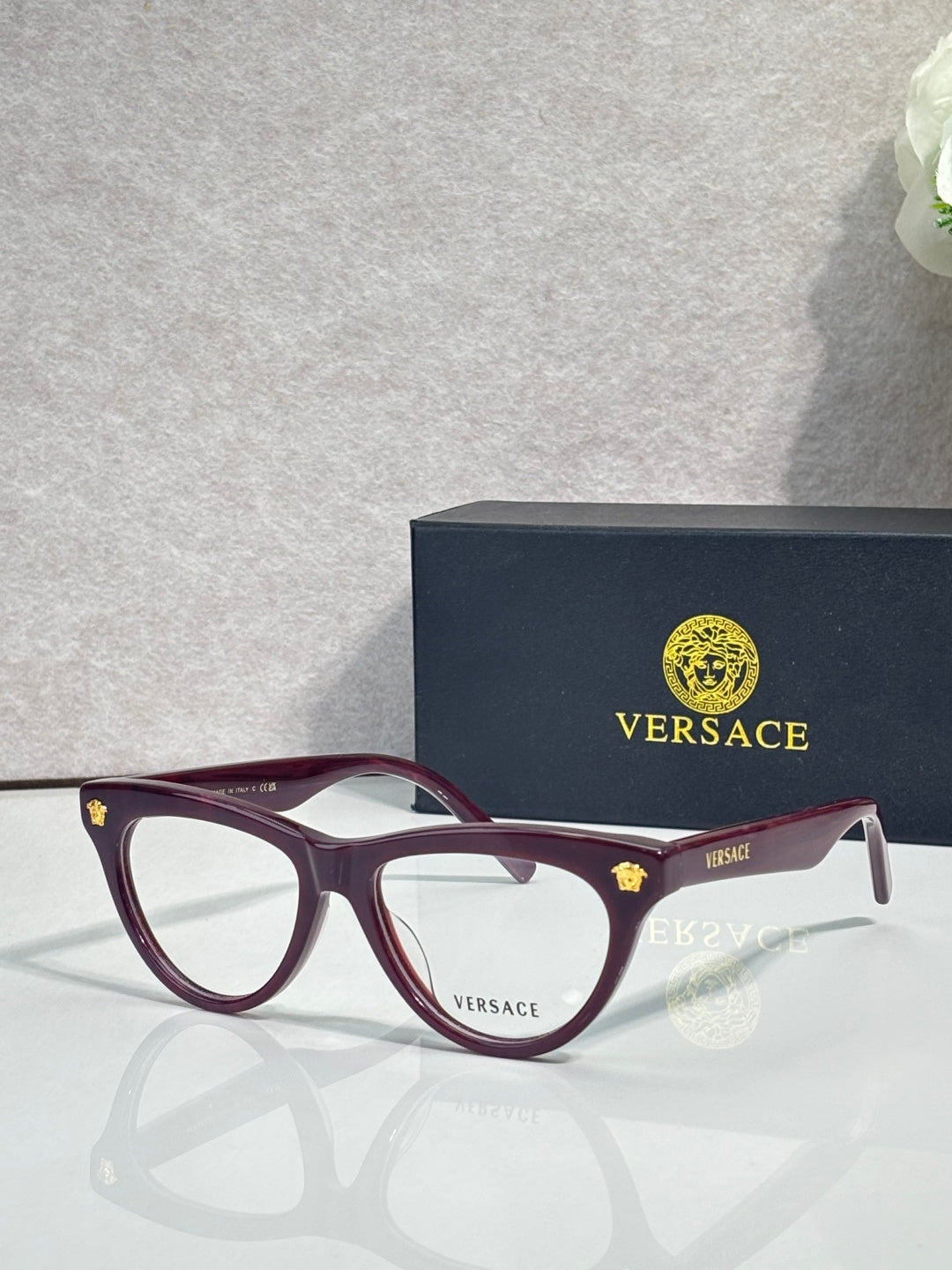 Versace optical glasses, burgundy frame with gold logo accents, clear lenses.