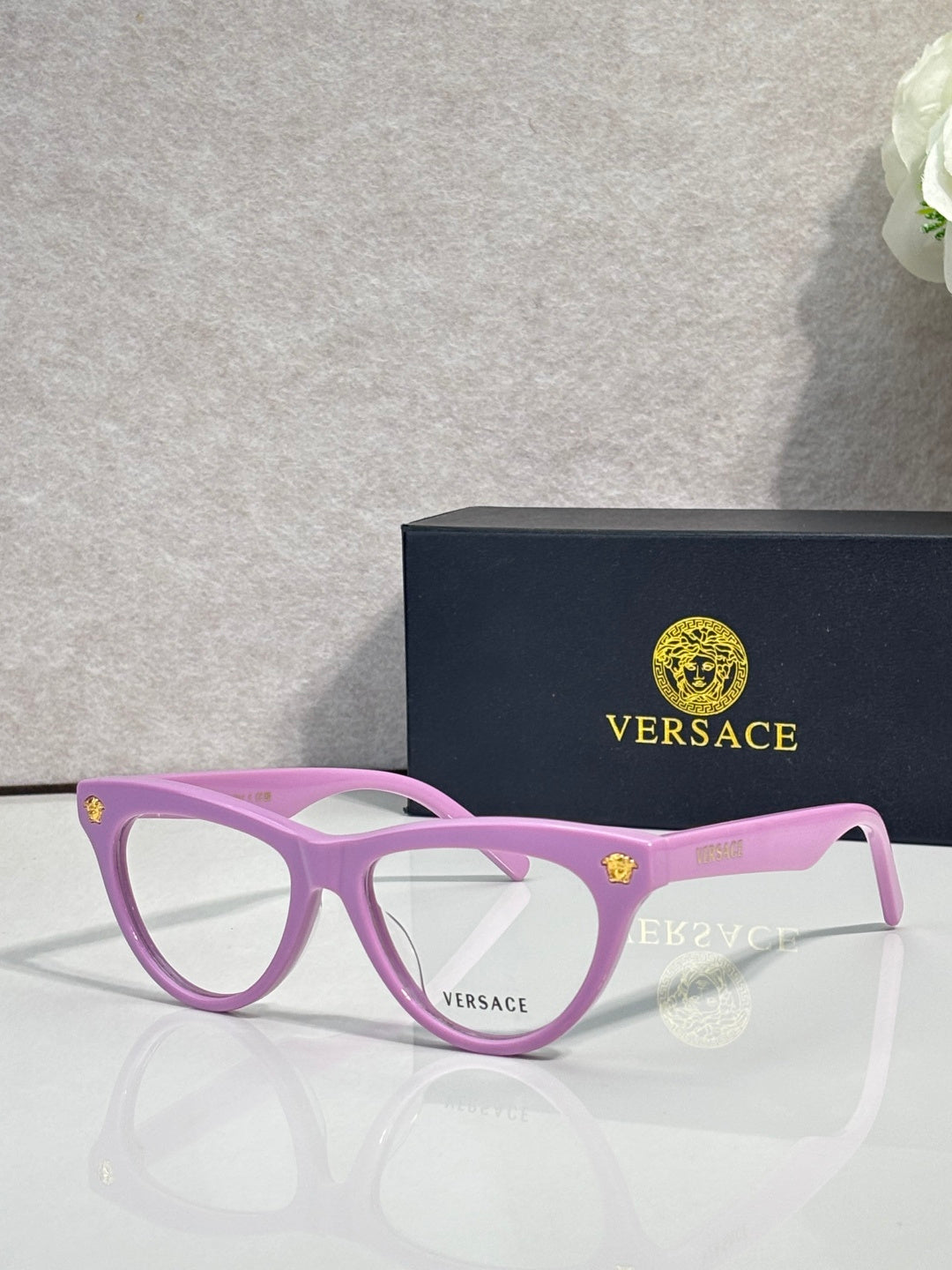 Versace optical glasses, pink frame with gold logo accents, clear lenses.