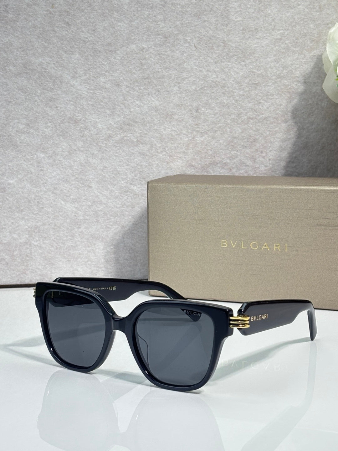 Black square sunglasses with dark lenses, gold-tone hinge detail, BVLGARI logo