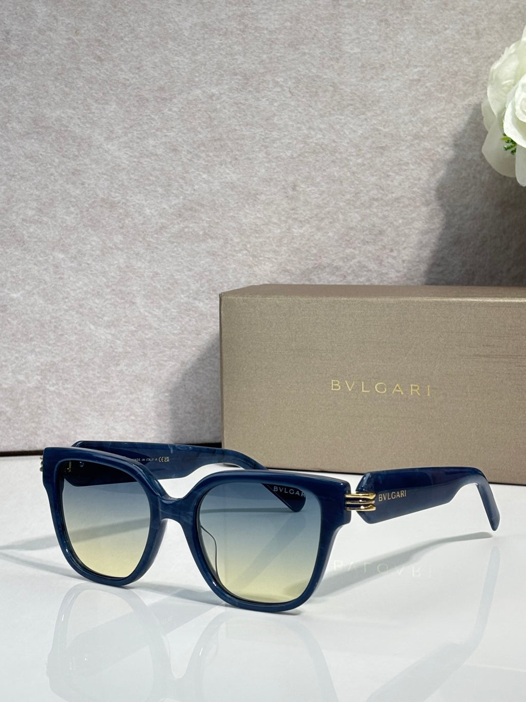 Blue square sunglasses with pale yellow-tinted lenses and gold-tone BVLGARI detail