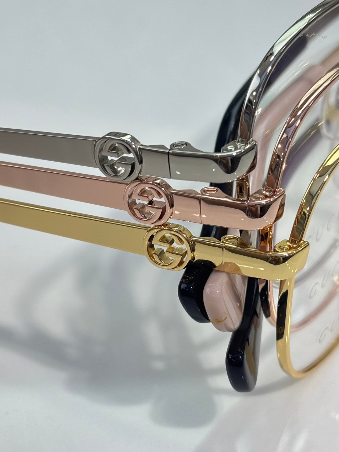 Eyeglasses hinge detail with silver and gold metal arms and round logo emblems