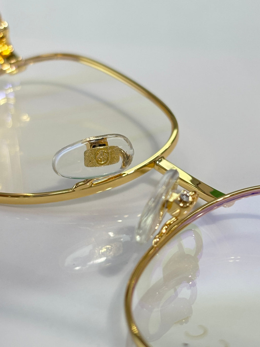 Gucci eyeglasses arm close-up with gold metal and logo hardware on clear lens