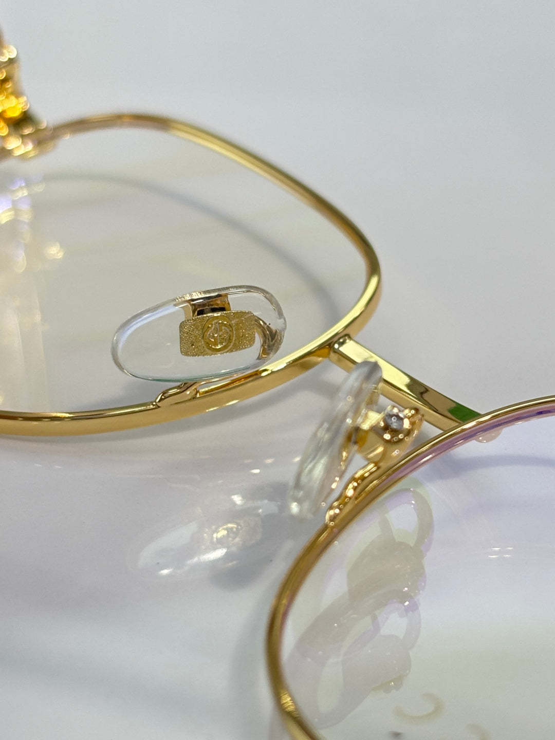 Gucci eyeglasses arm close-up with gold metal and logo hardware on clear lens
