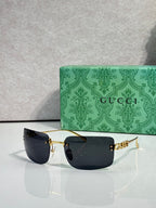 Sunglasses with gold frame and dark black-tinted lenses, Gucci logo on arm