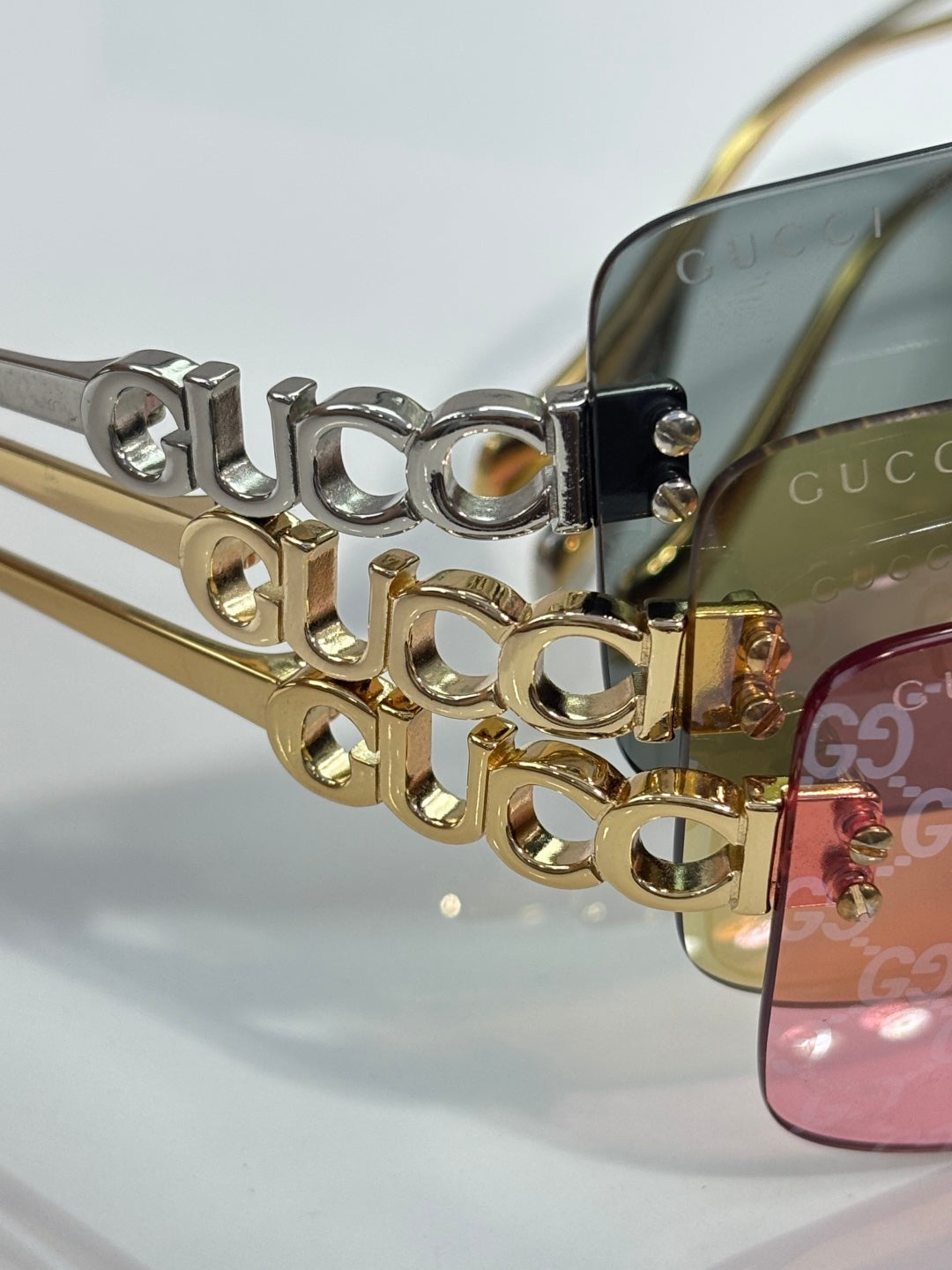 Sunglasses close-up: gold temple with Gucci lettering and pink-tinted lens edge