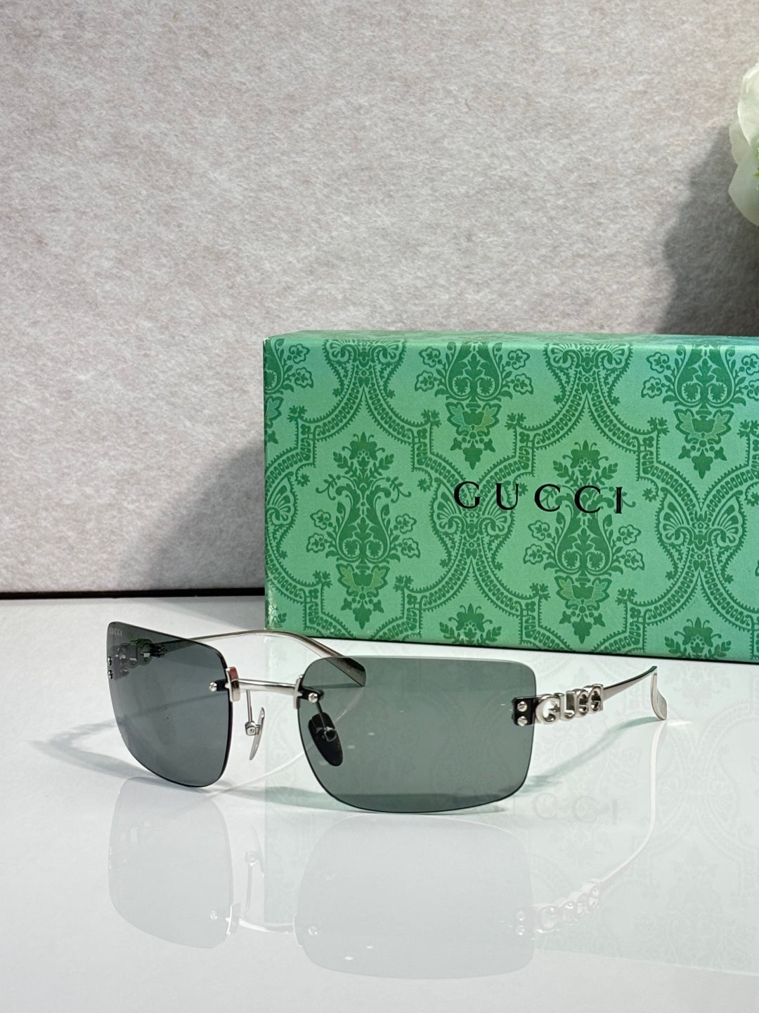 Sunglasses with gold frame and dark green-tinted lenses, Gucci logo on arm