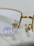 Cartier glasses close-up of gold frame bridge and side emblem, clear lenses
