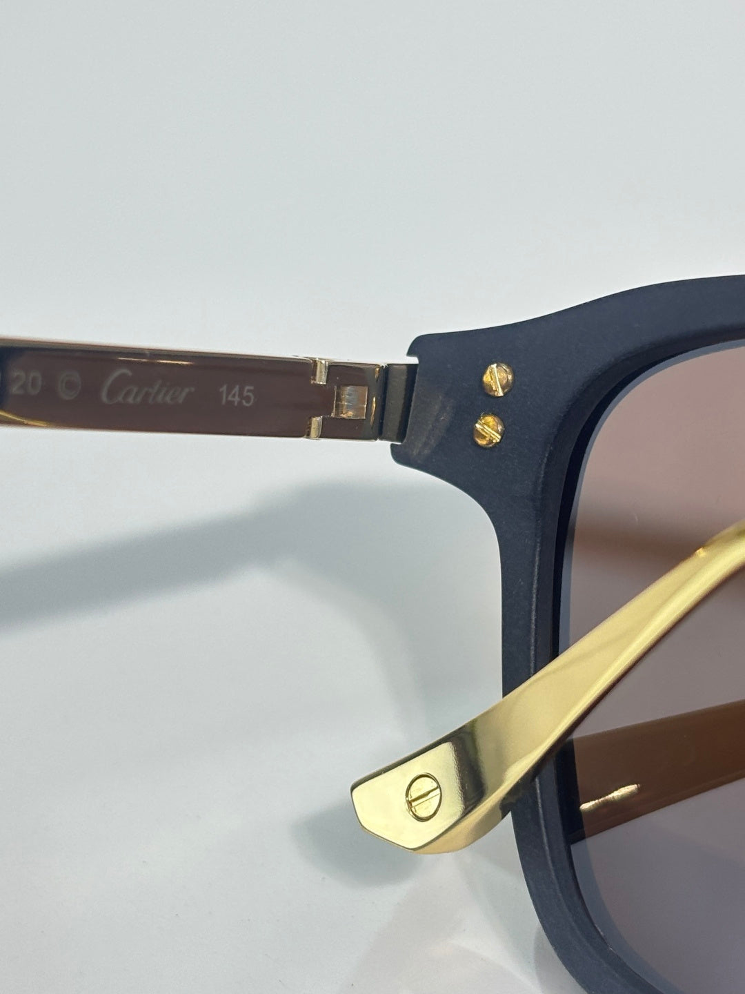 Dark blue eyeglass hinge with gold accent and metal frame arm