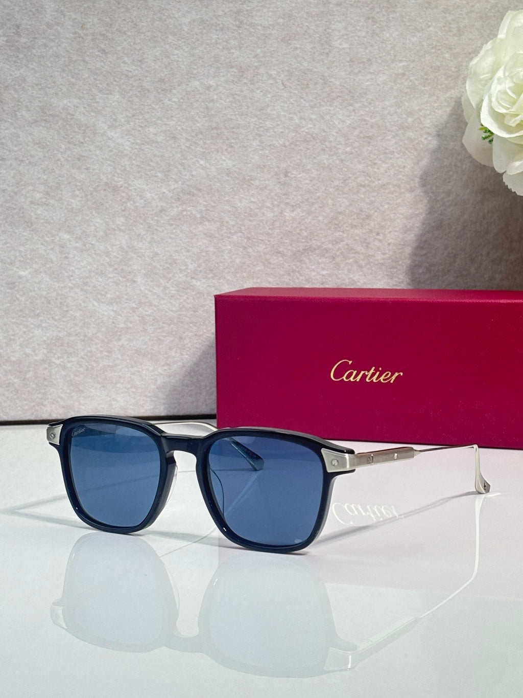 Blue eyeglasses with dark blue lenses, square frames, and gold-tone temple accents.