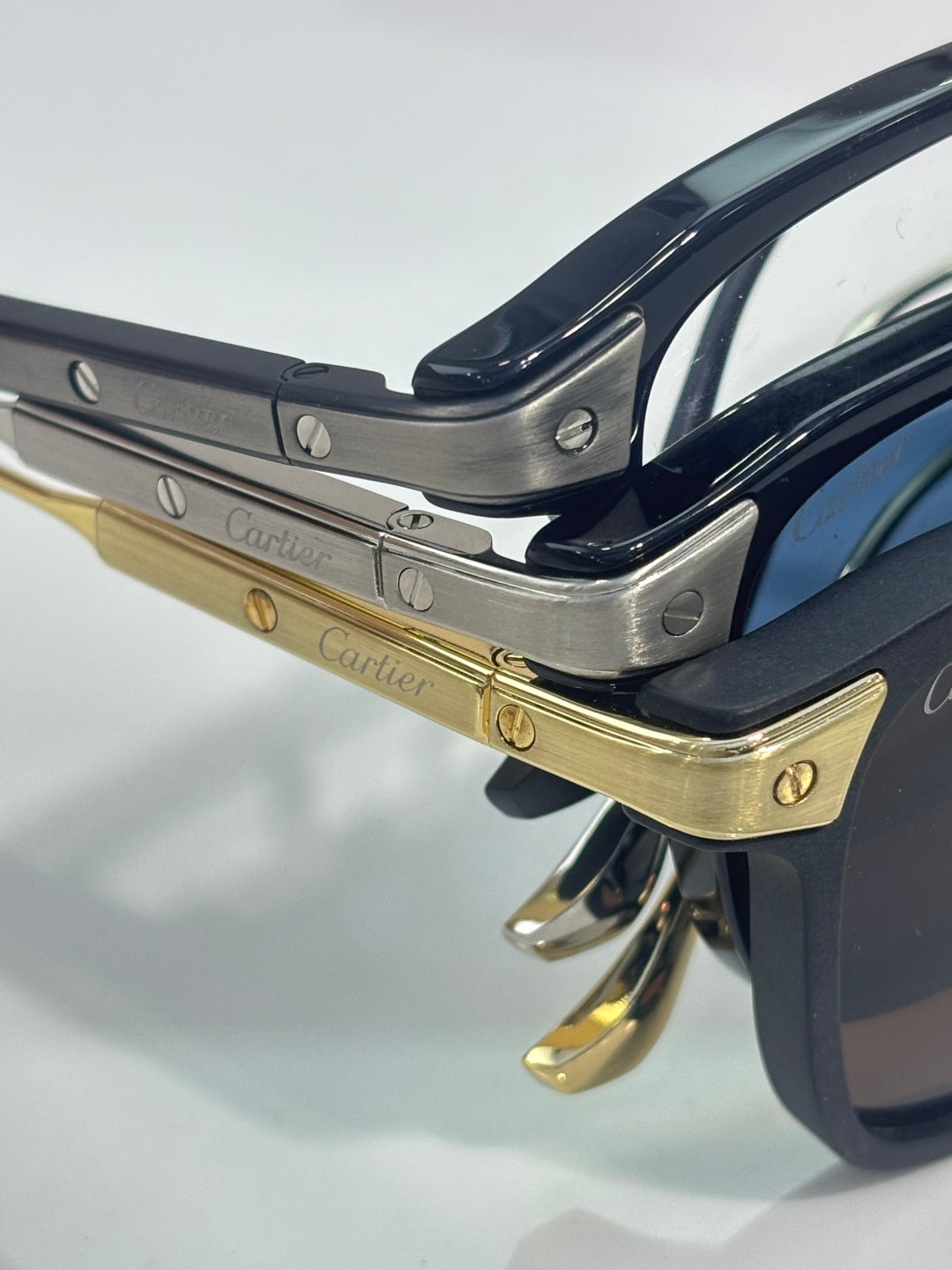 Close-up of navy eyeglass frame with gold-tone hinges and engraved metal temple details.
