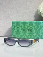 Gucci cat-eye sunglasses with dark frames and clear lenses, gold logo detail