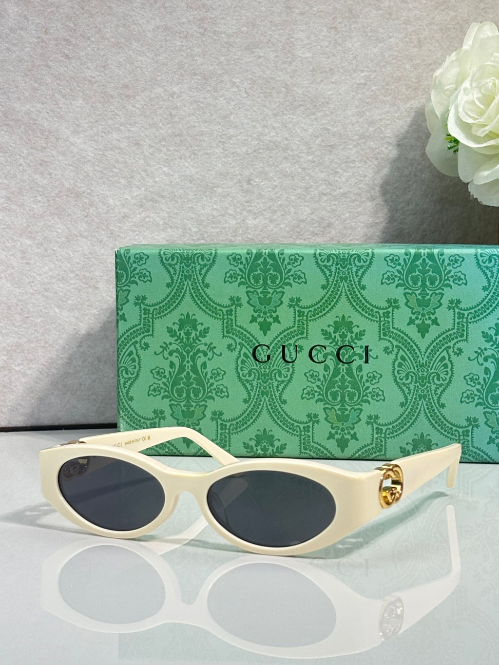 Gucci cat-eye sunglasses with cream frames, dark lenses, and gold logo hardware
