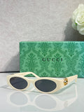 Gucci cat-eye sunglasses with cream frames, dark lenses, and gold logo hardware