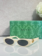 Gucci cat-eye sunglasses with cream frames, dark lenses, and gold logo hardware