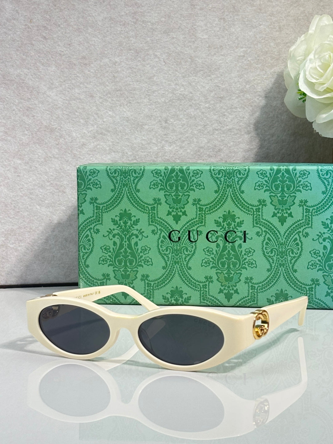 Gucci cat-eye sunglasses with cream frames, dark lenses, and gold logo hardware