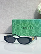 Gucci cat-eye sunglasses with dark frames and dark lenses, gold logo hardware