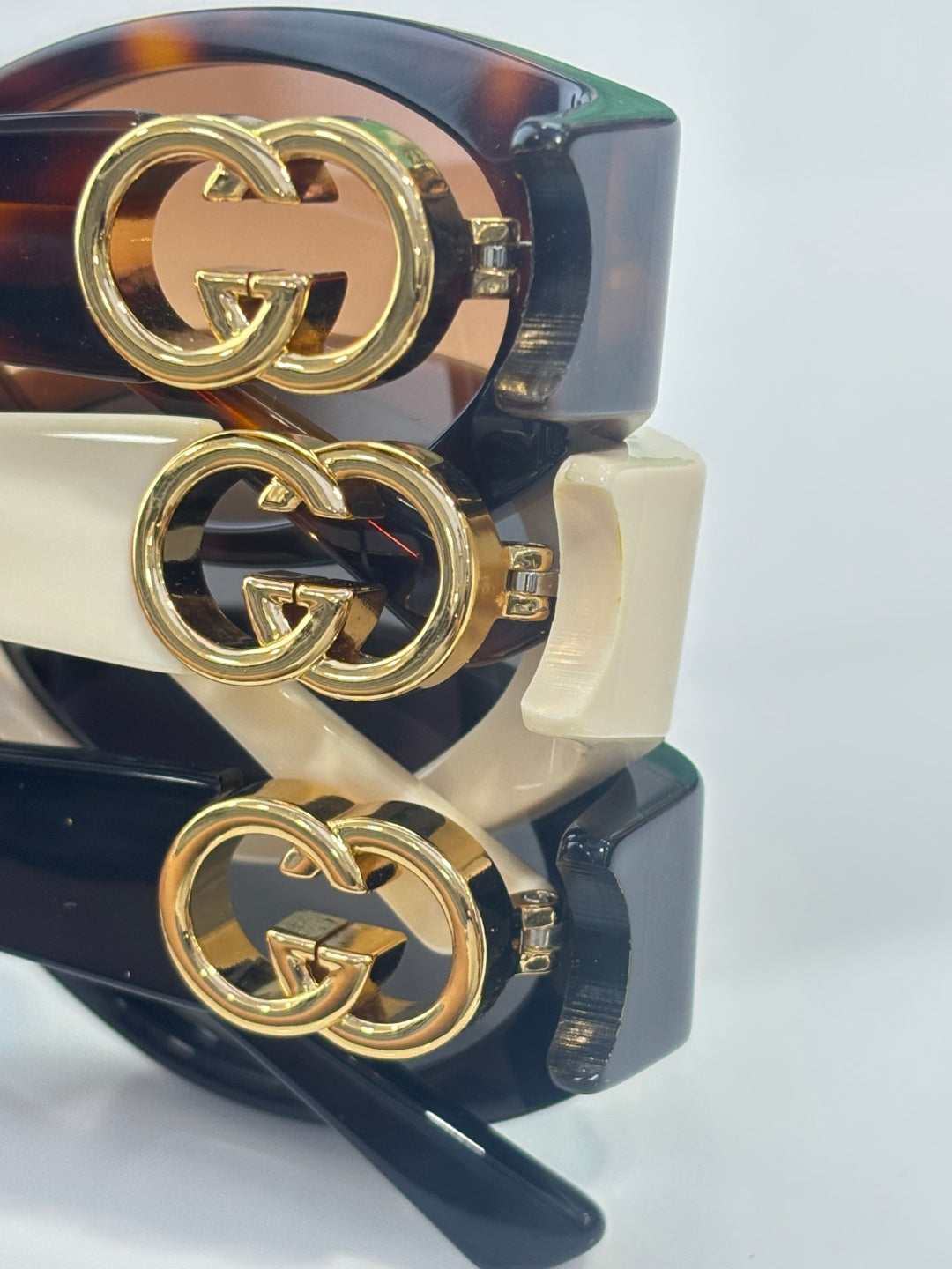 Gucci sunglasses side detail with gold GG logo hardware on dark tortoiseshell temple