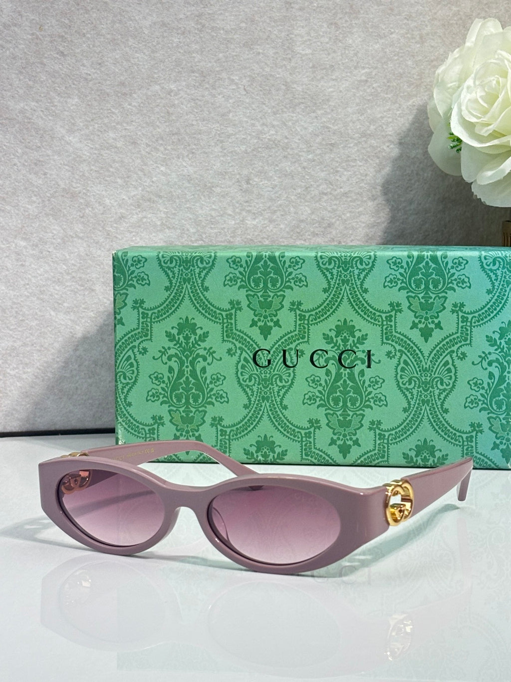Gucci cat-eye sunglasses with light pink lenses, pale frames, and gold logo hardware