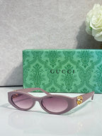 Gucci cat-eye sunglasses with light pink lenses, pale frames, and gold logo hardware