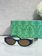 Gucci cat-eye sunglasses with dark frames, tinted lenses, and gold logo detail