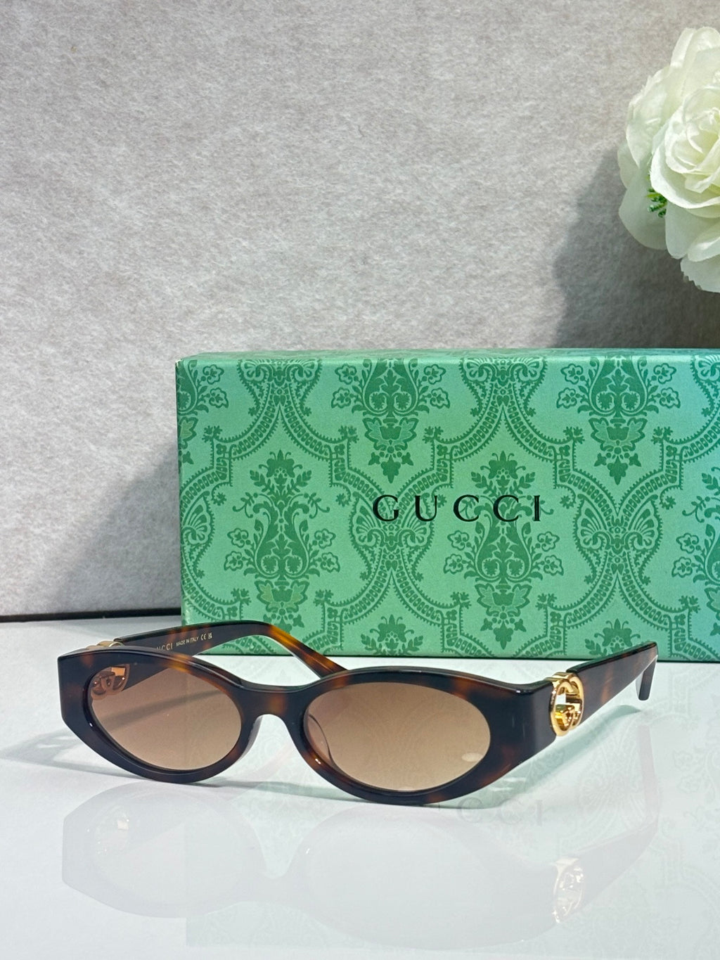 Gucci cat-eye sunglasses with dark frames, tinted lenses, and gold logo hardware