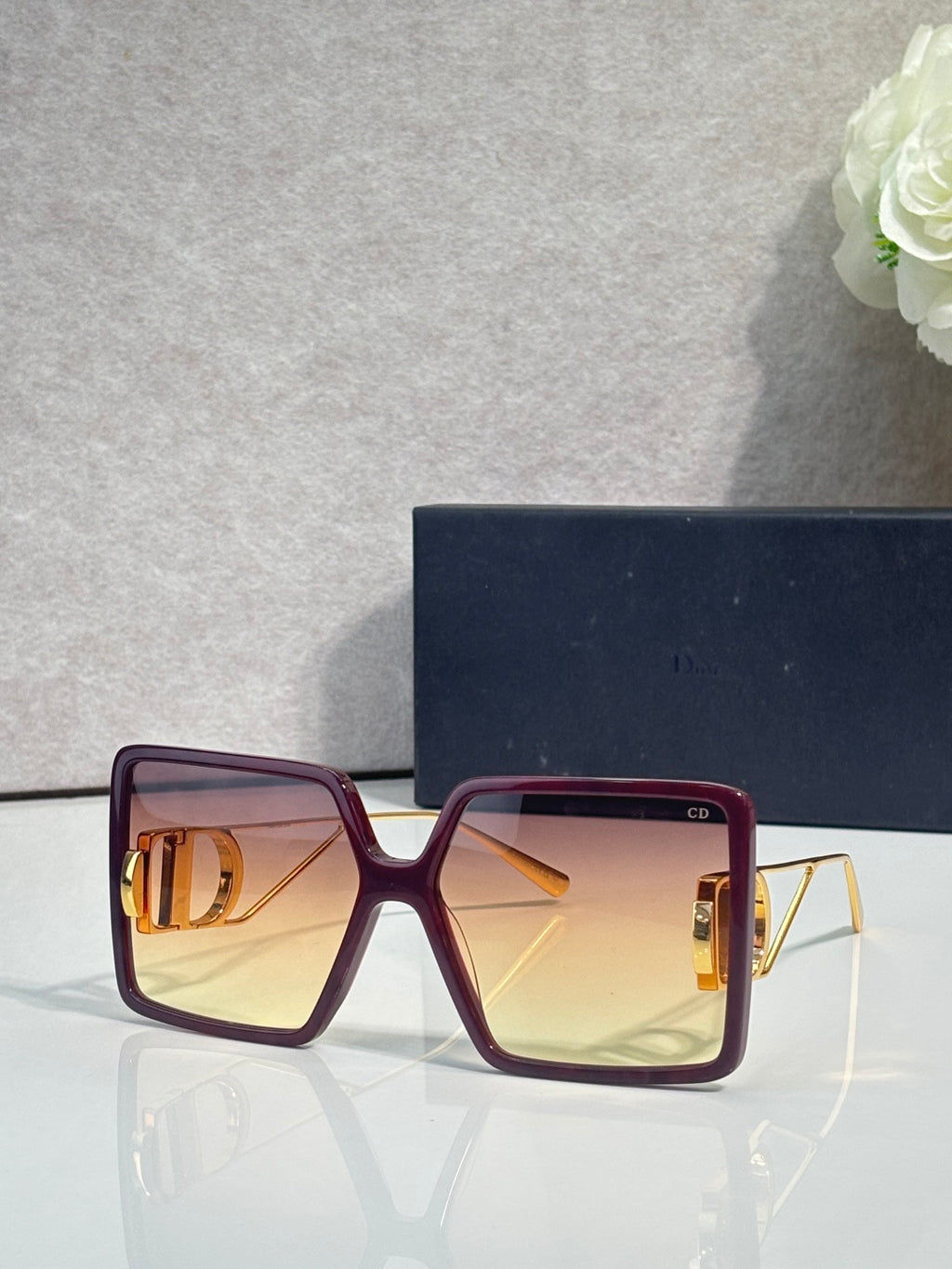 Dior sunglasses with dark maroon square frames and amber tinted lenses