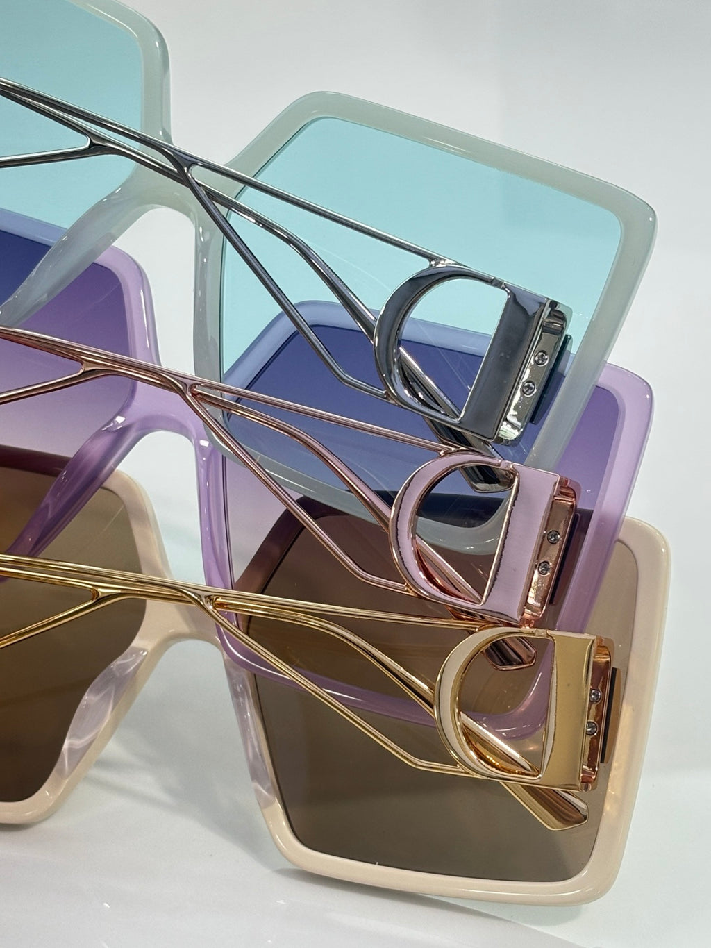 Assorted sunglasses frames in purple, blue, and cream with gold-tone hinges