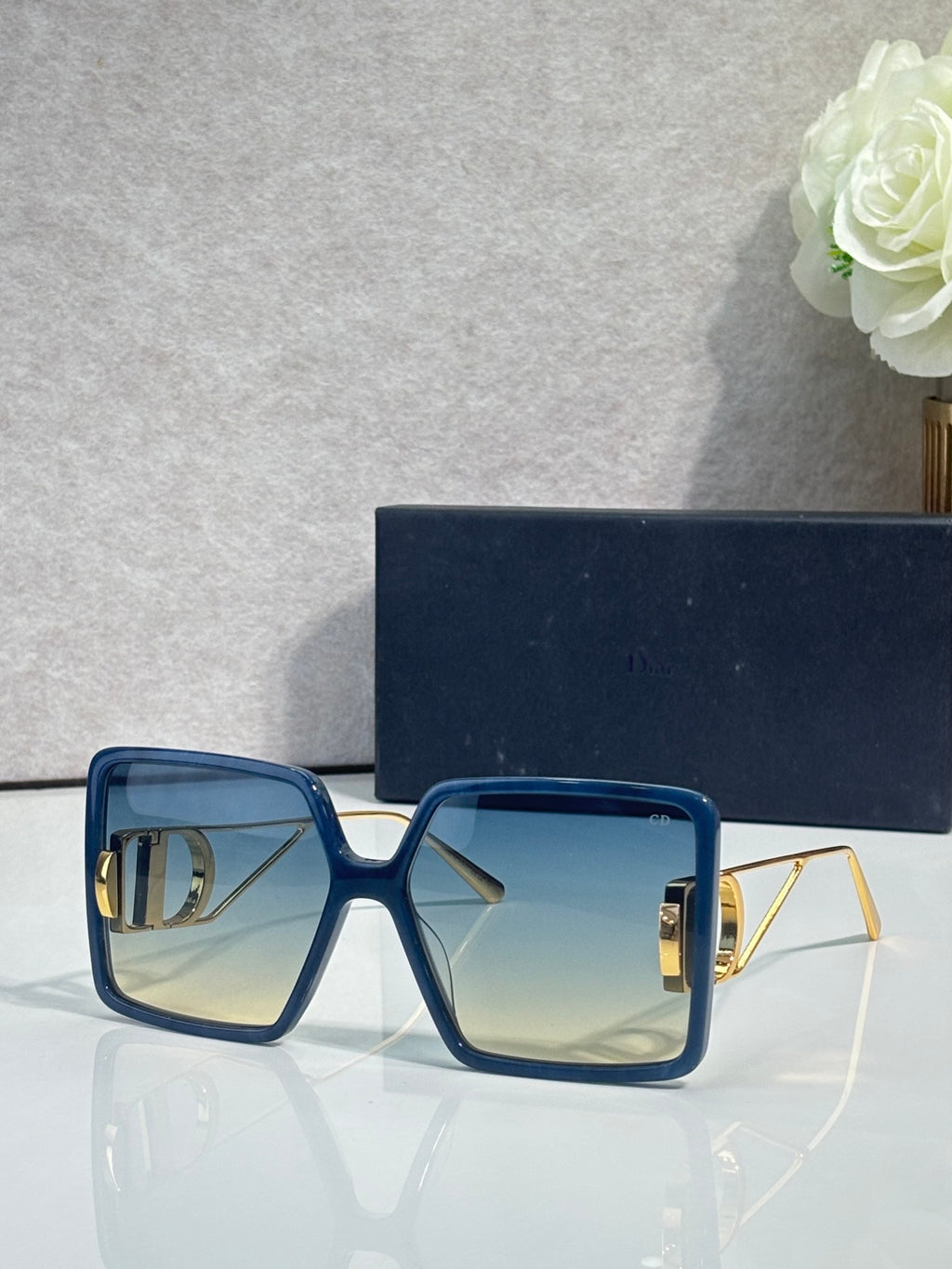 Blue square sunglasses with clear-to-light gradient lenses and gold-tone details