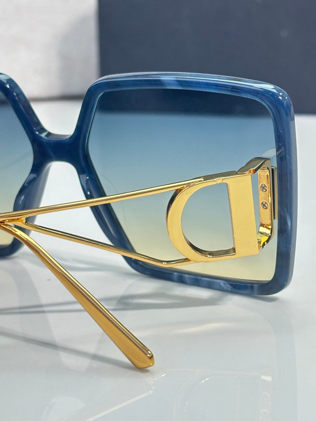 Blue square sunglasses with gold metal hinge and tinted lens