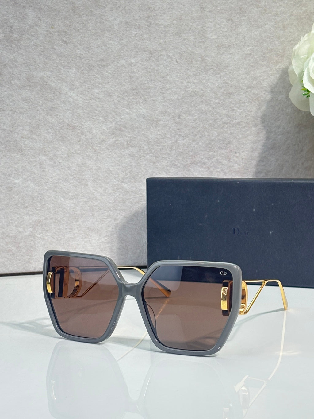 Dior sunglasses with dark blue thick frames and amber-tinted square lenses