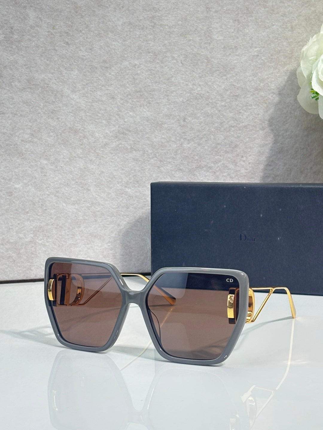 Dior sunglasses with dark blue thick frames and amber-tinted square lenses