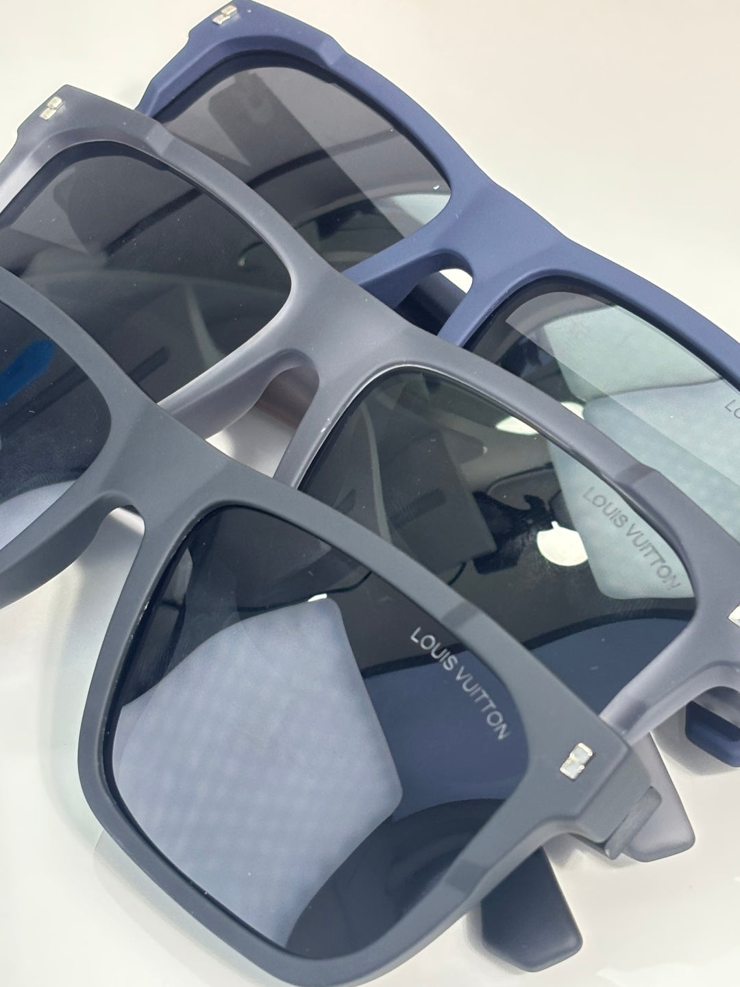 Louis Vuitton sunglasses close-up with light gray square frames and dark lenses