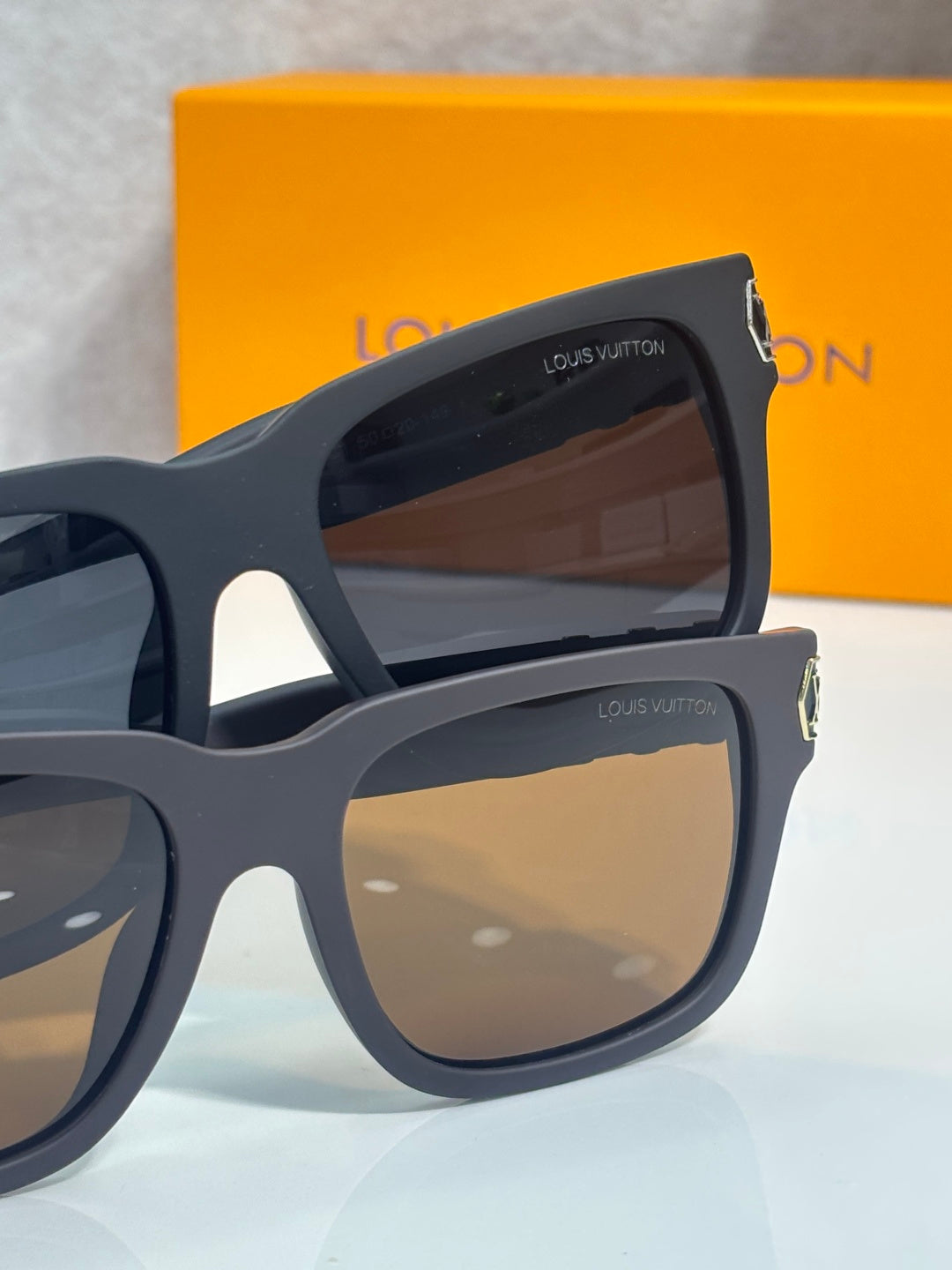 Louis Vuitton sunglasses with dark gray frames and brown tinted lenses, angled side view