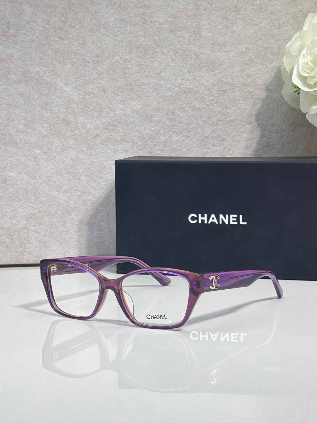 Purple and dark eyeglasses frame with square lenses and CHANEL logo on temple.