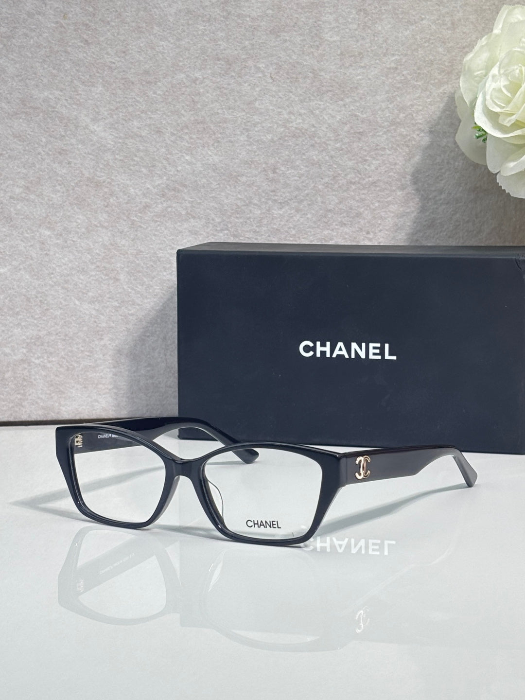 Black eyeglasses with square lenses and CHANEL logo on temple, full frame.