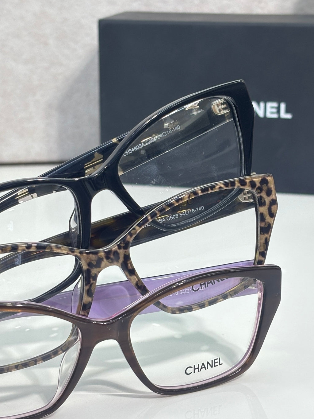 Leopard-print and dark eyeglasses frames with square lenses and CHANEL branding.